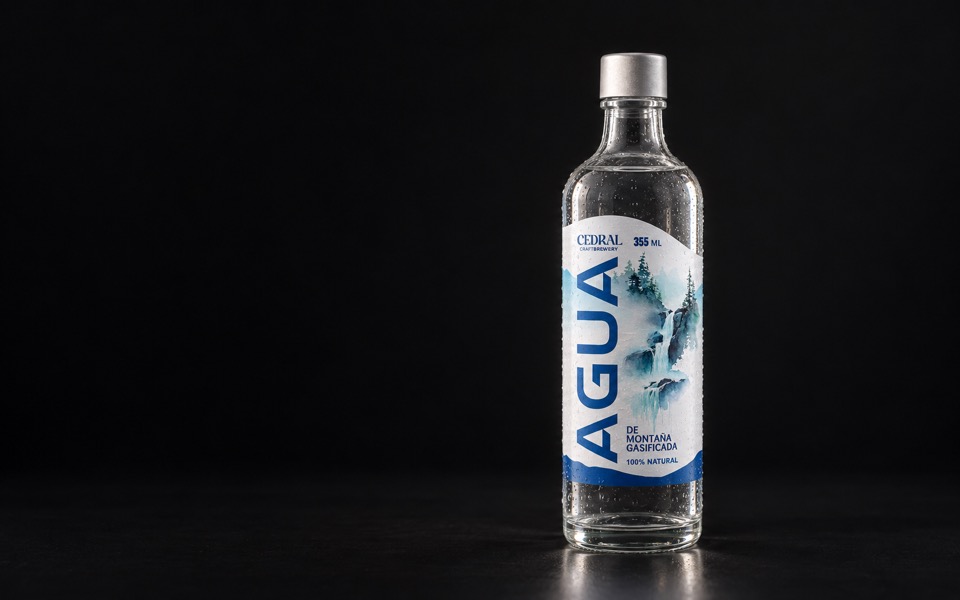 Botella de 355 ml como objeto premium: vidrio, condensación fina, transparencia, burbujas, iluminación editorial.
